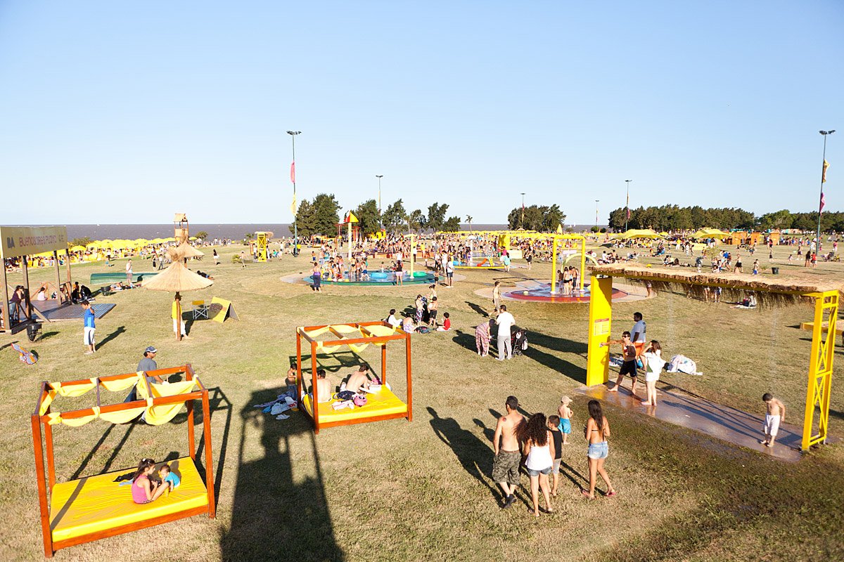El Parque de los Niños en un día de sol, con juegos y gente en el pasto