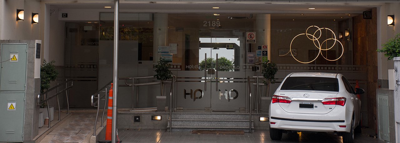 La entrada del hotel con la cochera y el cartel encendido
