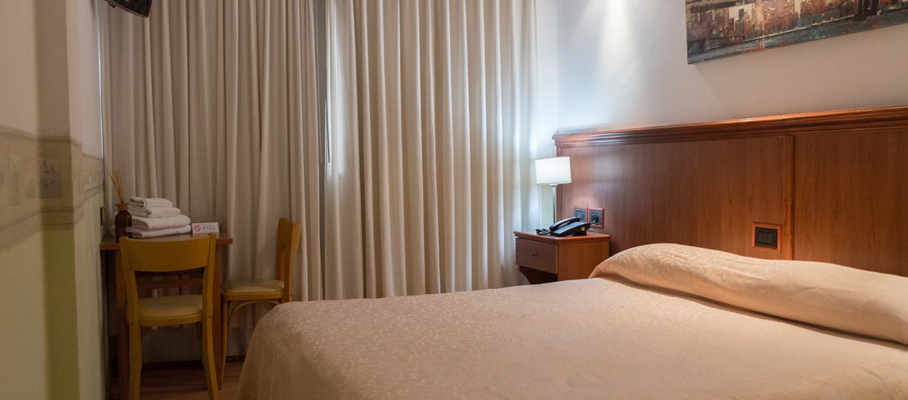 Habitación matrimonial con cama de dos plazas, TV y cortinados