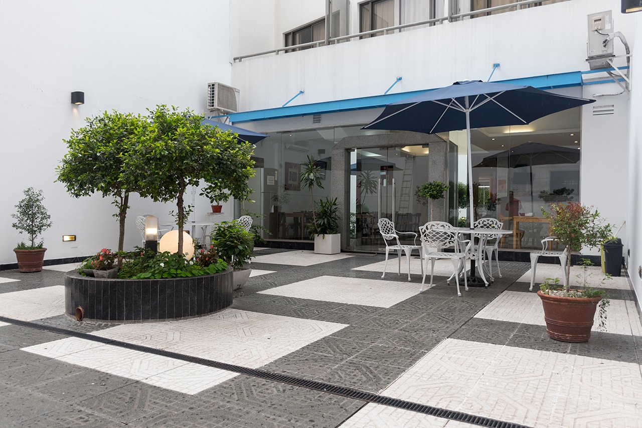 El patio interno del hotel con piso damero, plantas y mesas de jardín